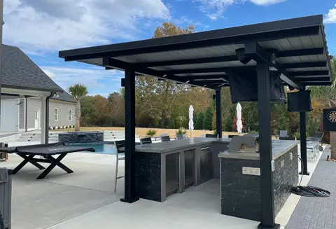 A black outdoor kitchen with an umbrella over the grill.